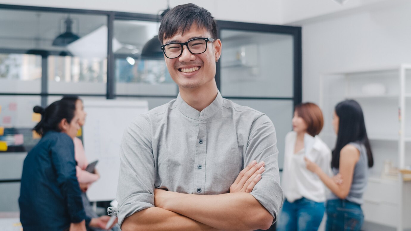 a young man in glasses standing in an office | ask2axcel