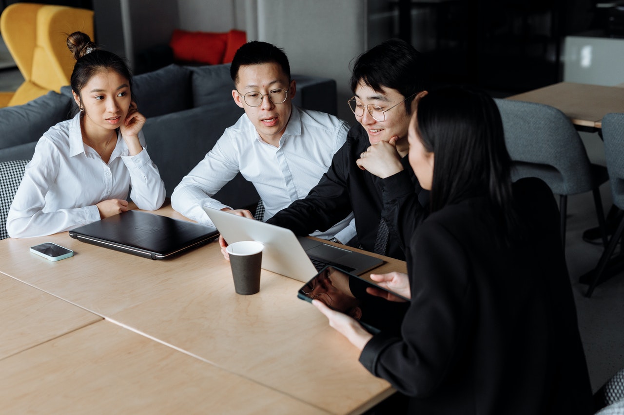 three people sitting at a table with a laptop