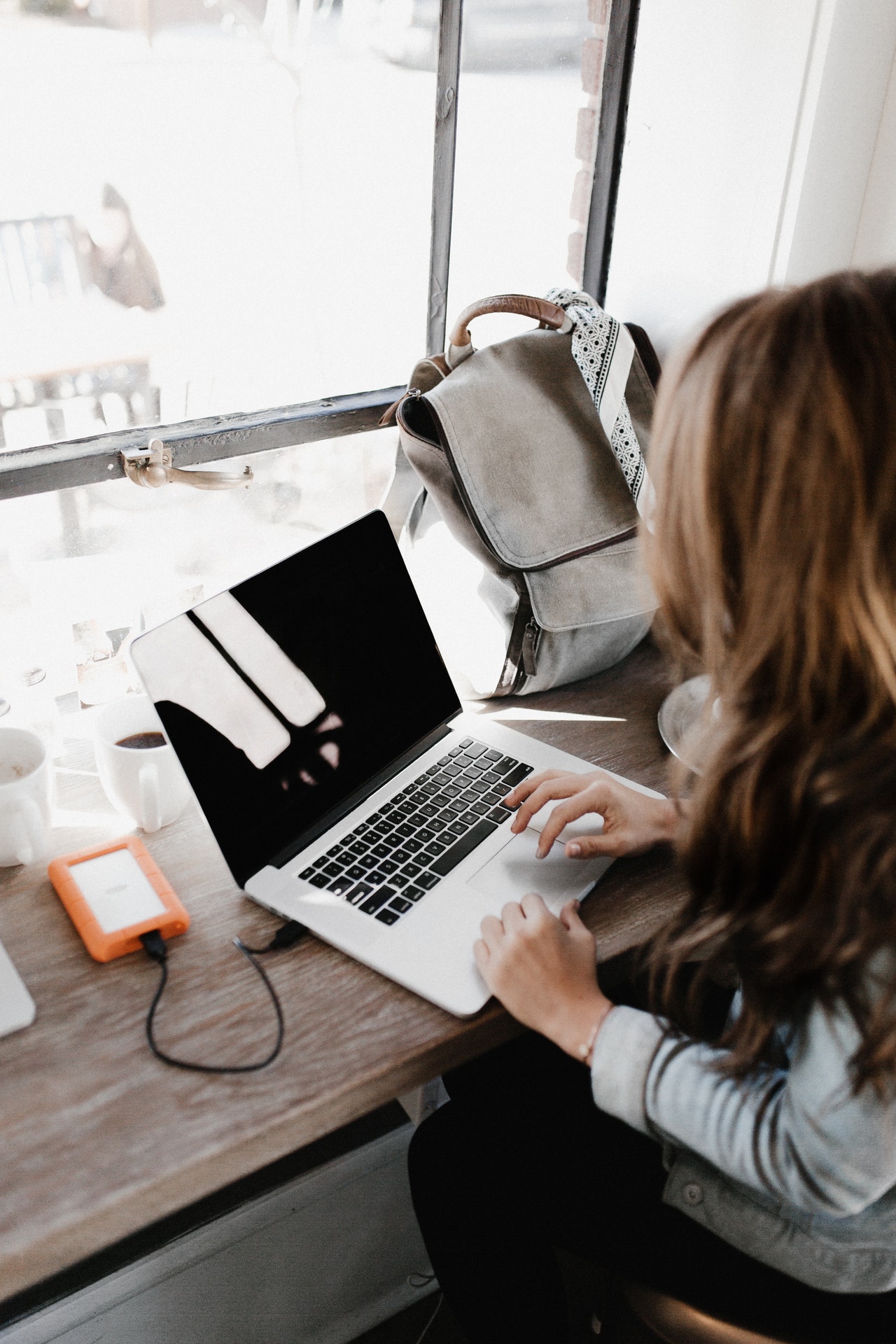 a woman sitting at a table with a laptop | ask2axcel