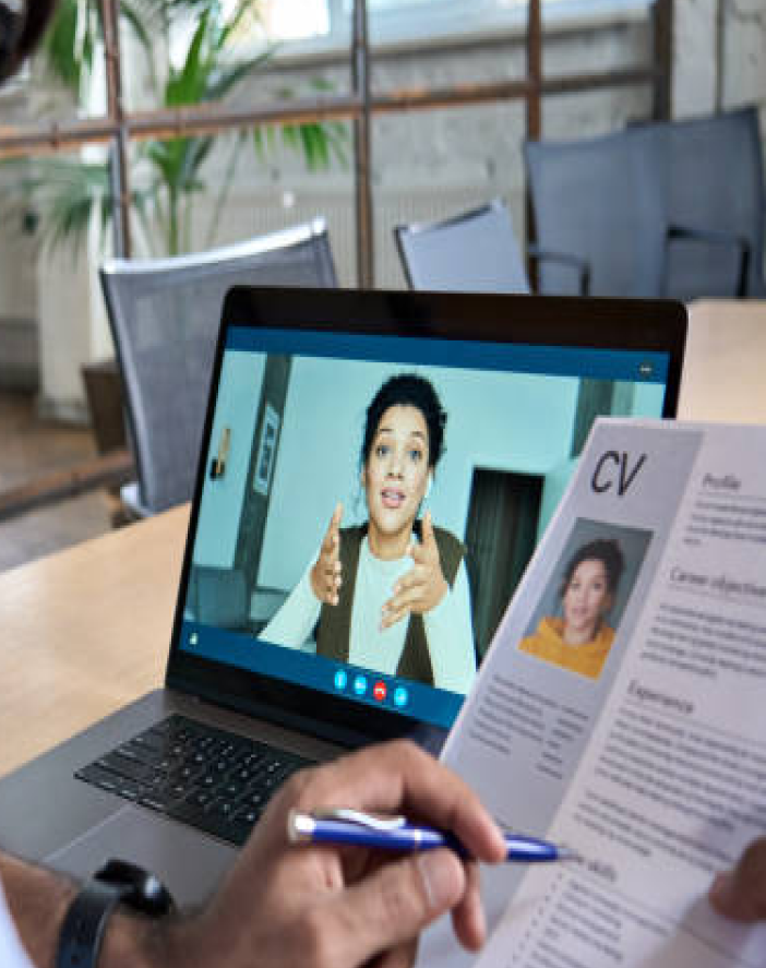 a man is sitting at a table with a laptop and a video conference