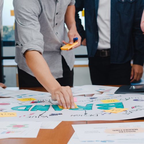 a group of people standing around a table with papers | ask2axcel